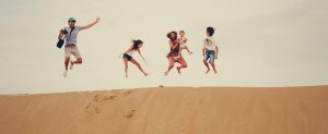 Familie springend in het zand